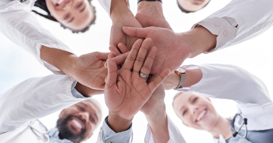 Doctors Partnering and stacking their hands on top of each other to physically show a partnership